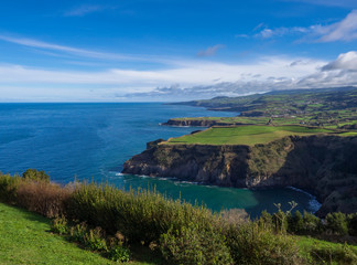 green fields pasture and coastal cliffs and blue ocean and sky horizon at north coast of sao miguel island, Azores, Portugal