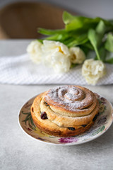 baked bun on a colorful plate, on a marble backdrop, homemade, tulips on background