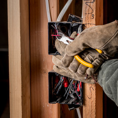 Construction electrician clips a wire in new home construction