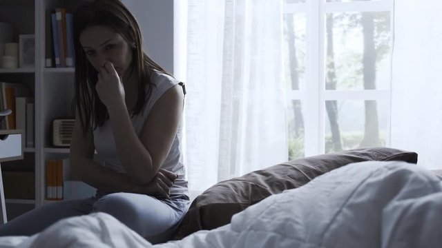 Concerned woman sitting on her bed and thinking