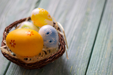 Easter card with painted eggs on the wooden table, with flower and grass