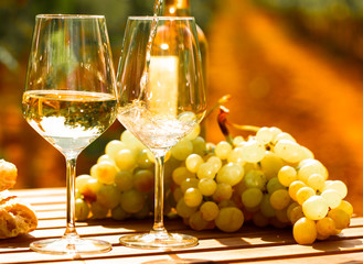 glass of White wine ripe grapes and bread on table in vineyard