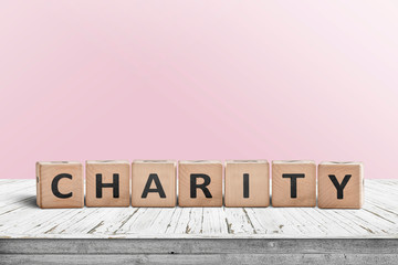 Charity sign on a wooden desk with a pink wall