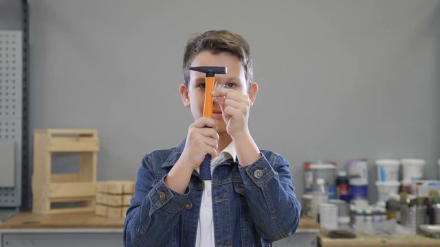 Boy and building implements with Hammer and nails in hands closing and opening eyes smiling. Handcraft concept. hobby and leisure time at locksmiths workshop. 4k
