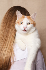 Gentle white cat on a woman's shoulder. White cat on the shoulder of a blonde on a beige background