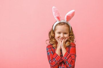 Obraz na płótnie Canvas Portrait of a cute little child girl with bunny ears on a colored background. Happy easter