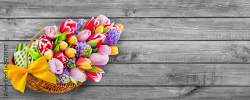 Springtime flowers and basket on wooden background