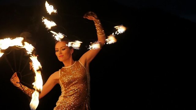 Amazing art action at open air. Attractive girl model juggling igniting sparkling torches slowmotion. Actress entertaining tourists, twilight spectacle in amphitheater. Program in all inclusive tour