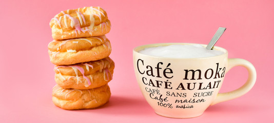 a large Cup of cappuccino coffee and a lot of with donuts, Breakfast concept, a Cup in french written mocha coffee, coffee with milk, coffee without sugar. pink background, selective focus