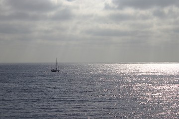 Ein Segelboot fährt auf dem Ozean in den sonnenuntergang.