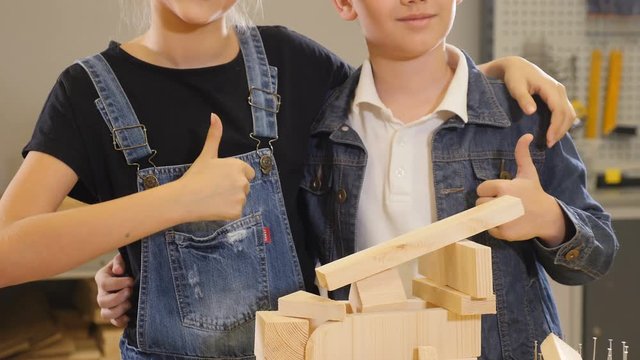Little masters at work. Little designers. Unrecognizable in carpentry or craft workstudio. Thumb up. Little helpers. 4k