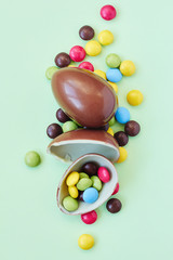 Chocolate Easter eggs and sweets on pastel green background
