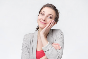 Young woman wearing casual clothes smiles being pleased dreaming about vacation.