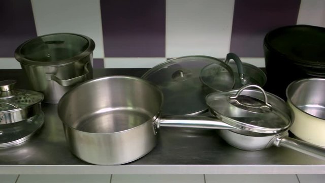 Stainless steel cookware at kitchen. Clean pans and pots on table. Steel kitchenware set.