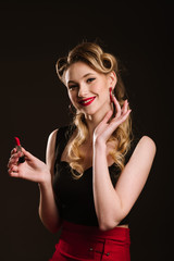 Woman in retro style posing with a red lipstick on the black background. Pinup portrait