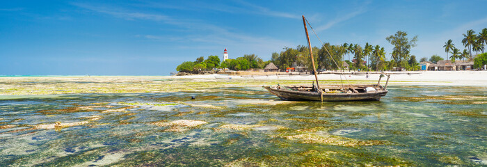 panorama of low tide with lighthouse and boat in Zanzibar island in Tanzania - obrazy, fototapety, plakaty