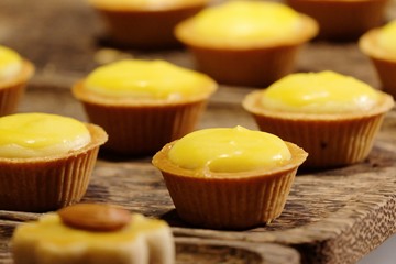In selective focus a row of lemon cheese tartlets on wooden table with warm light
