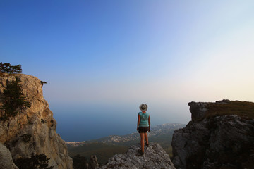 Girl in a hat on the edge of a cliff