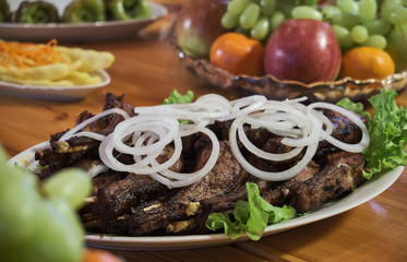 Overhead view of colorful roast vegetables, savory sauces and salt served with grilled t-bone steak on a rustic wooden counter in a country steakhouse