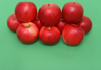Big piramid of red apples on the green background
