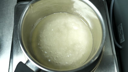Boiling and bubbling sugar syrup and agar-agar in a saucepan on an electric cooker for making syrup, confectionery