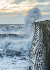 Stormy sea crashing over Tynemouth Pier, Tyneside, Engalnd, UK . In early morning light and sunrise.