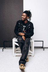 One attractive smiling black man in black jacket and black pants over gray background