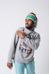 Portrait of a smiling black young model in a gray sweater and blue pants on a gray background