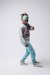 Portrait of a smiling black young model in a gray sweater and blue pants on a gray background