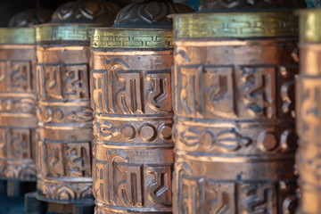 Golden buddhist prayer wheels. Tibetan symbols and mantra Om mani padme hum