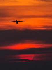 Fototapeta na wymiar Air plane taking off at sunset near to the sun with beautiful red cloud in background
