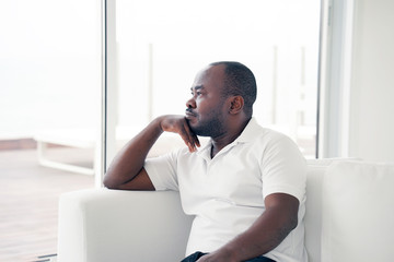 Lonely african man is sad sitting on the bed. Portrait of a sad male close-up. Man feel depression.