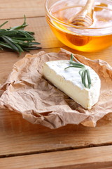 Camembert with rosemary branches on wooden boards. Soft cheese on parchment paper. Cheese with and honey on wooden background