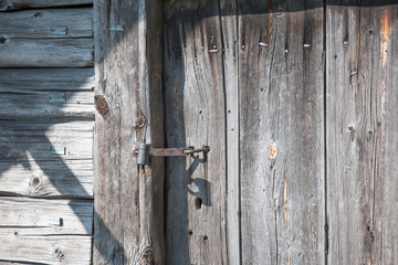 Rusty  lock on the wooden doors. Lock on the door of an old farmhouse. Village style. Close-up. Wooden texture. Natural wood background.