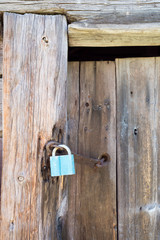 Rusty blue lock on the wooden doors. Lock on the door of an old farmhouse. Village style. Close-up. Wooden texture. Natural wood background.