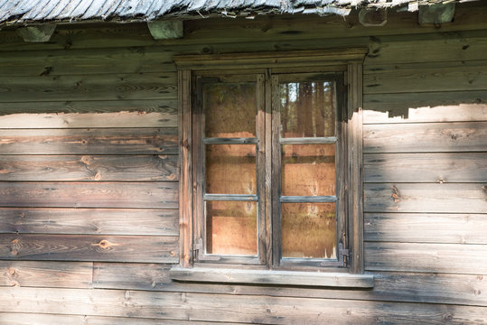 An old window in a wooden house. A small window in the wall of an old, rustic wooden house. Closed.