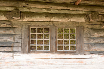 Vintage, authentic natural wood house wall with big  double windows. Old weathered wooden plank background in brown color. Wood texture. Very old farm/ village house. Place for text. Copy space.