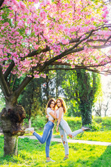 Naklejka premium two girls hug and raised their feet in the park with japanese ch