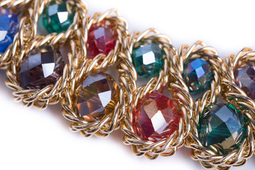 Costume jewelry, factory-produced mass product. Golden look necklace with colored glas gemstones isolated on white background. Top view. Beautiful jewelry with green, red, blue, brown, yellow, purple 