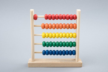 Traditional counts/abacus with colorful wooden beads on gray background. Toy abacus to learn counting. Colorful children counting frame for kids. Counts show: one. Copy space. Top view. 