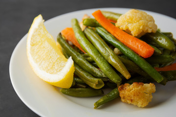 Vegetarian food. Cooked tir, green beans with carrots and lemon, on white plate. Famous Chinese cuisine. Healthy food.