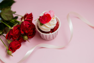 cupcake roses and hearts on a pink background.copy spase.Chocolate cupcakes decorated with cream rose