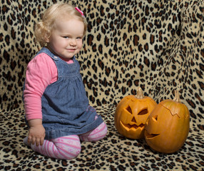 a little blonde girl is interested in two cut for halloween pumpkins