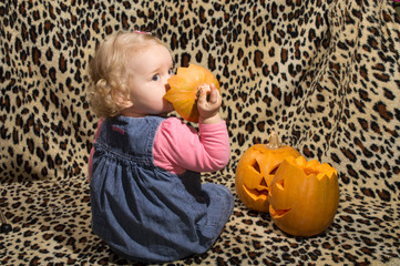 a little blonde girl is interested in two cut for halloween pumpkins