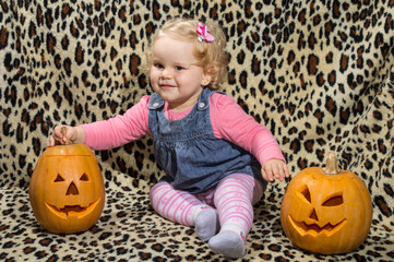 a little blonde girl is interested in two cut for halloween pumpkins