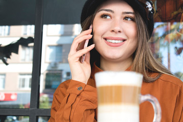 Young woman at cafe drinking coffee and talking on the mobile phone