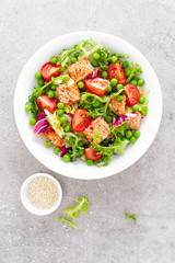Healthy lunch vegetable salad with baked salmon fish, fresh green peas, lettuce and tomato. Top view