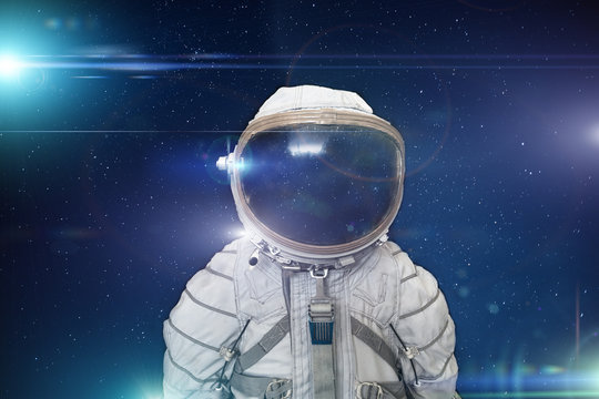 Retro cosmonaut or astronaut or spaceman with helmet on space with stars and blue light effects background, abstract science fiction concept