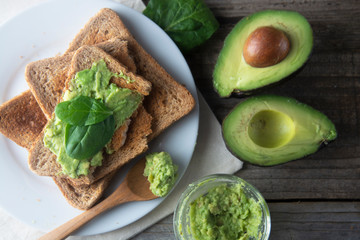 Delicious wholewheat toast with guacamole, avocado slices. Mexican cuisine. Healthy food, snack. Breakfast. Wooden rustic table.