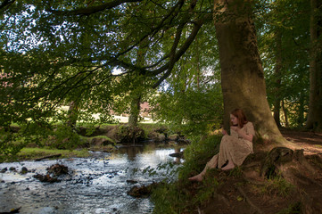 Young female in the forest next to a river